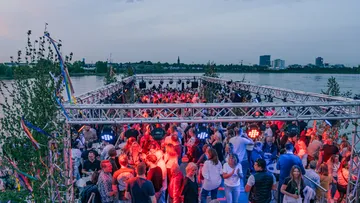 Menschenmenge tanzt auf einem Boot bei Sonnenuntergang.