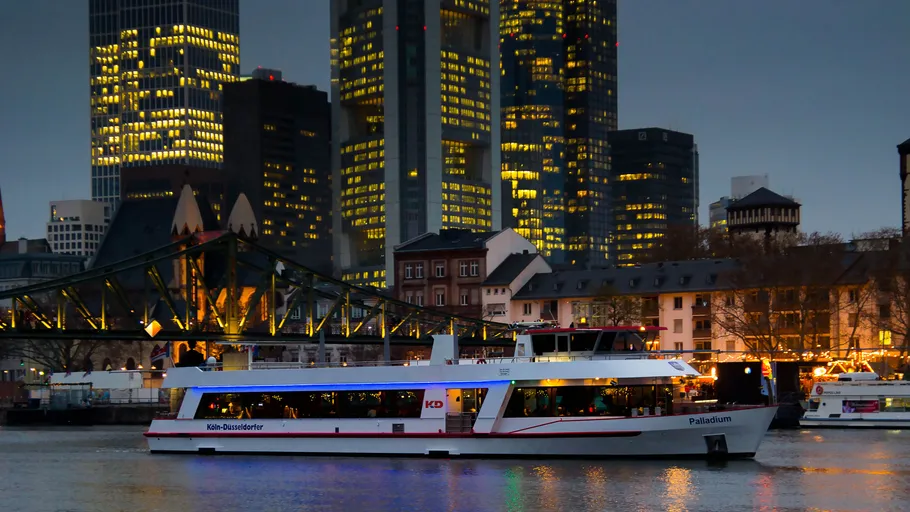 Boat sailing on river with city skyline.