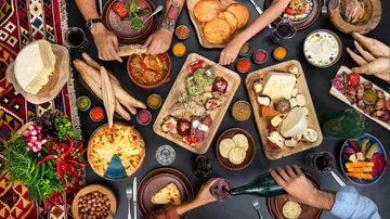 Table with diverse foods and hands reaching.