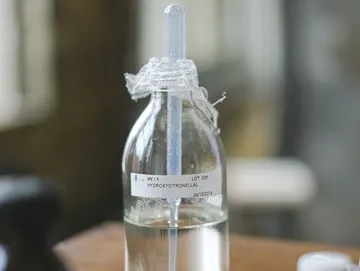 Flasche mit Pipette, gefüllt mit Flüssigkeit, unscharfer Hintergrund.