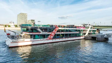 Passagierschiff legt an städtischem Flussufer an.