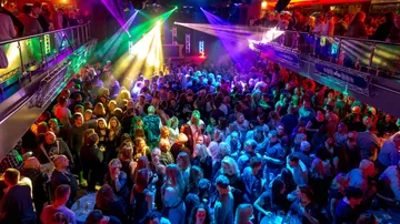 Überfüllter Nachtclub mit bunten Lichtern und Tanzenden.