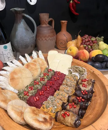Holzplatte mit verschiedenen Speisen und Krügen.