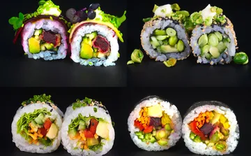 Bunte Gemüsesushi-Rollen auf schwarzem Hintergrund.