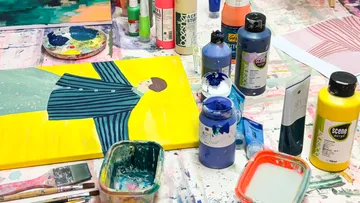 Painting materials on cluttered art studio table.