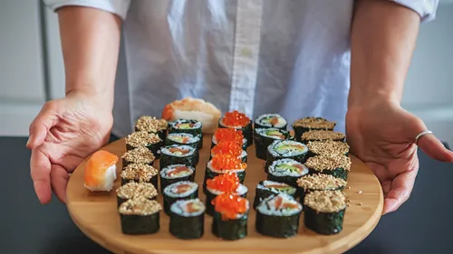 Person holding platter of assorted sushi.