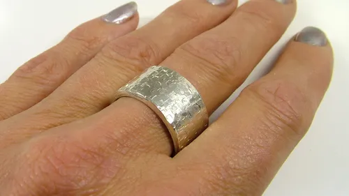 Breiter Silberring an einem Finger.