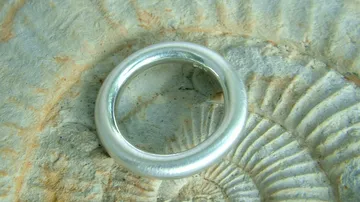 Silberner Ring auf Fossilienstein Hintergrund.