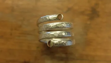 Gespiralter Silberring auf Holzoberfläche.