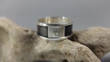 Silberner Ring mit Pfotenabdruck auf Treibholz.