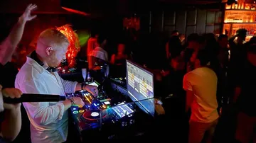 DJ performing in a dimly lit nightclub.