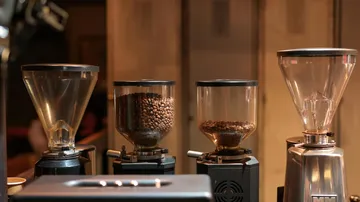 Four coffee grinders in a café setting.