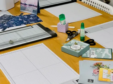Paper, pens and tools lie on a table.