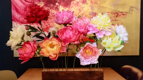Colorful paper flowers in a wooden vase.