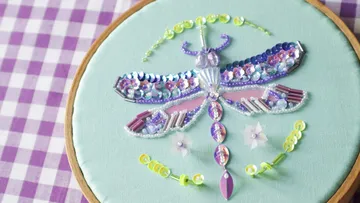 Beaded dragonfly artwork on green fabric.