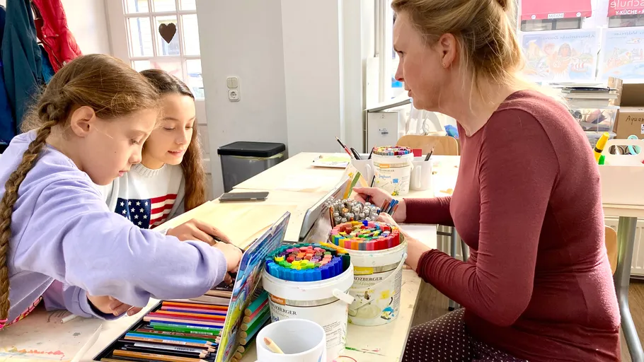 Children and teacher coloring at a table.