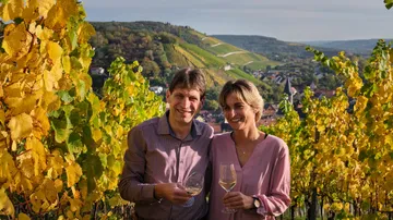 Paar hält Weingläser im Weinberg.
