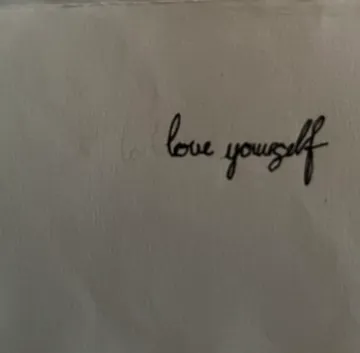 Handwriting on paper, saying 'love yourself'.