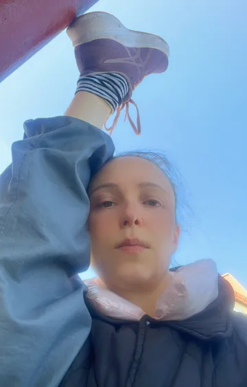 Person doing a leg stretch outdoors, sunny day.