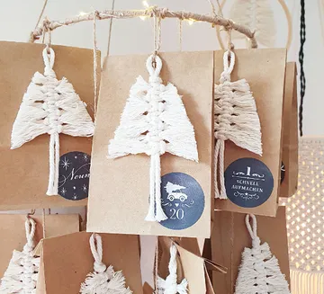Dekorative Papiertüten hängen mit weißen Weihnachtsbaum-Anhängern.