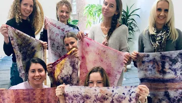 Women displaying colorful handmade scarves indoors.