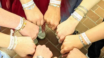 Hands with friendship bracelets in a circle.