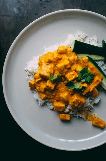 Curry on rice with cucumber slices.