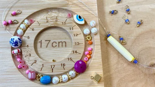 Beads on wooden circular ruler, crafting setup.