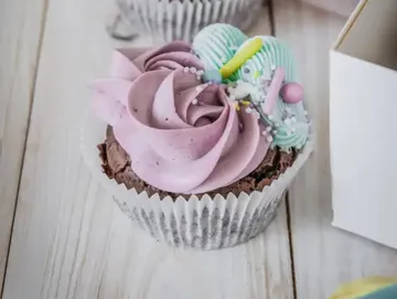 Cupcake mit dekorativer Glasur auf Holzoberfläche.