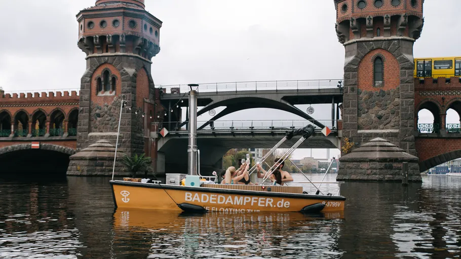 Boat with sauna near historic bridge.