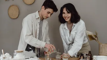 Zwei Personen machen Kerzen an einem Tisch.