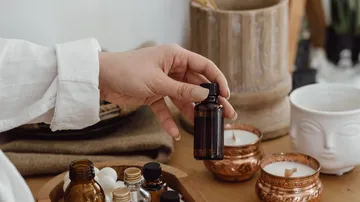 Hand hält Flasche in gemütlicher Umgebung.