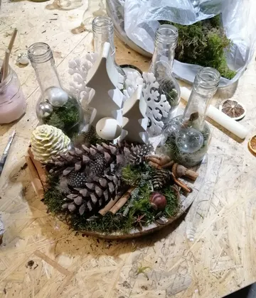 Christmas decoration with pinecones and bottles on table.