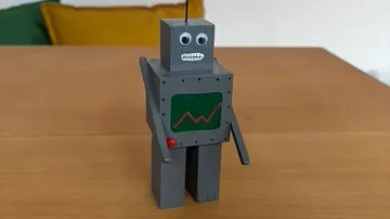 Graues Roboterspielzeug auf Holztisch.