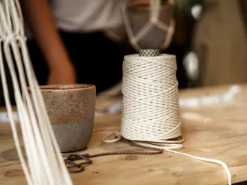 Rolls of string and cup on a wooden table, creative environment.