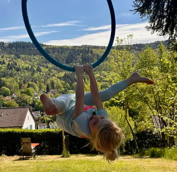 Child swinging on a hoop in garden.