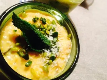 Creamy dessert topped with mint leaf and pistachios.