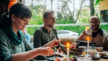 Drei Personen genießen Mahlzeit in gemütlichem Restaurant.