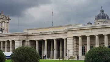 Neoclassical building with columns under cloudy sky.