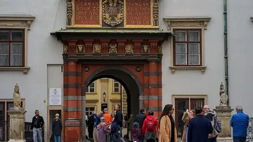 People walking through historic arched entrance.
