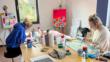 Two women painting in a studio.