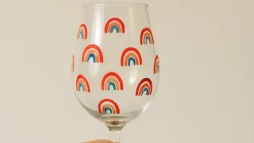 Weinglas mit Regenbogenmustern, schlichter Hintergrund.