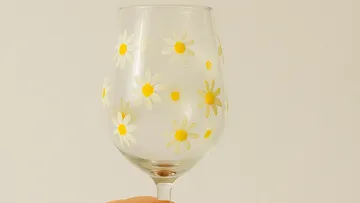 Weinglas mit gelben Gänseblümchen verziert.