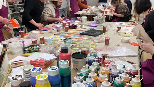 People painting at a long, colorful table.