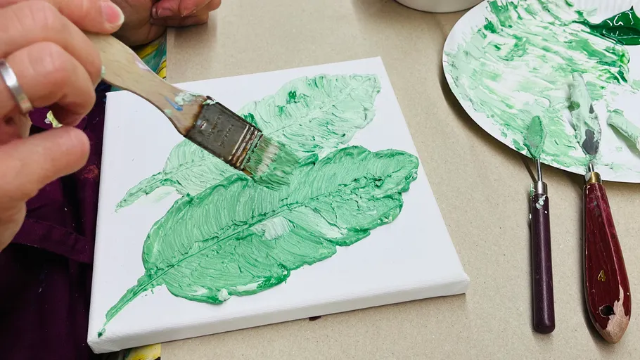 Hand painting green leaves on canvas.