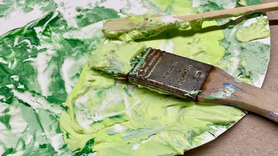 Pinsel auf Palette mit grüner Farbe.