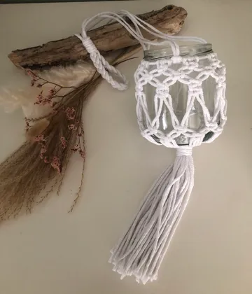 Macramé jar holder with wooden branch and dried flowers.