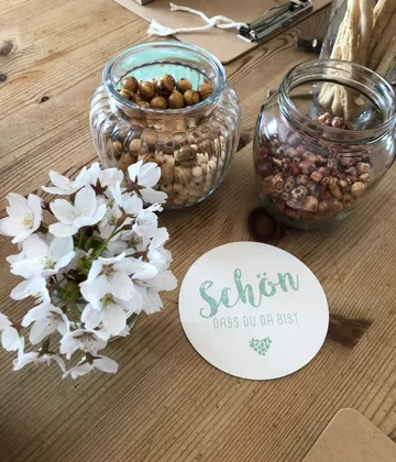 Gläser mit Perlen, Blumen und Karte.