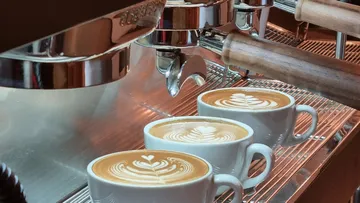Espresso machine preparing lattes with latte art.