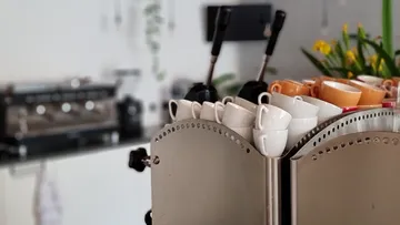 Coffee cups stacked on espresso machine.